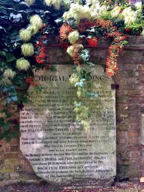 Brick wall, with history plaque and autumnal flowers